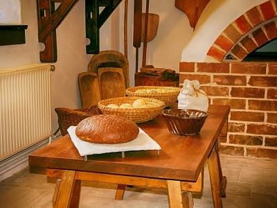 Traditionelle Backstube mit einem Tisch mit Broten bestückt und Backschaufeln im Hintergrund. Gemütliche Bäckerei mit Backschaufel.